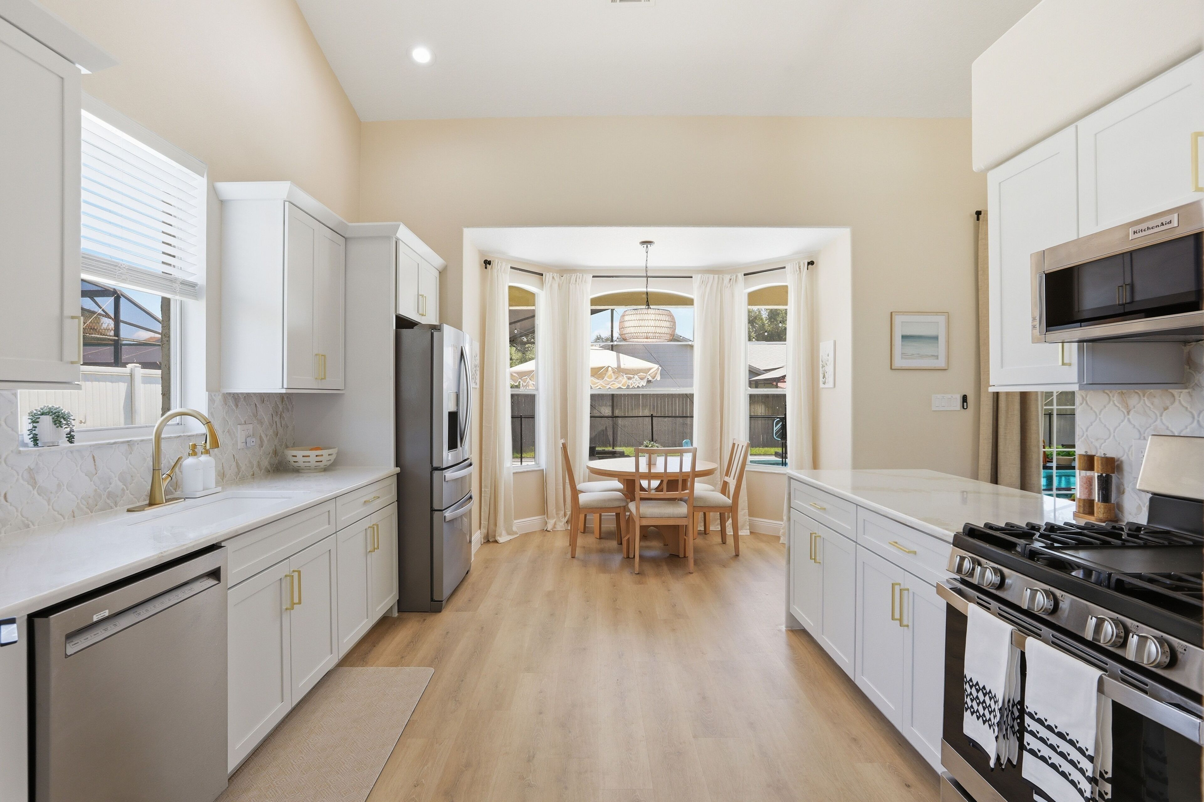 A modern kitchen with white cabinetry, a built-in oven, and a gas stove.