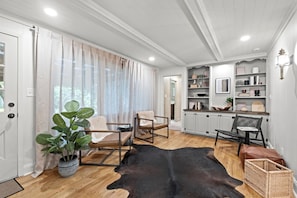 A spacious living room with a wooden floor, a cowhide rug, and a potted plant. - The Mini Glenwood - Reimagined Ranch in Mission, KS (Mission)