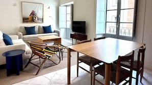 A living room with a sofa, chairs, a coffee table, a TV, and a dining table. - Alameda Grand Luxury (Seville)