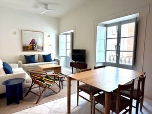A living room with a sofa, chairs, a coffee table, a TV, and a dining table. - Alameda Grand Luxury (Seville)