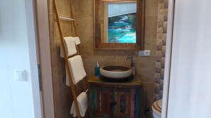 Et badeværelse med en træstige, en håndvask, et spejl med et maleri, og et toilet.