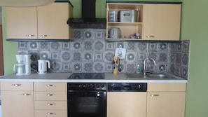 Een keuken met een vaatwasser, koffiezetapparaat, broodrooster en een spoelbak.