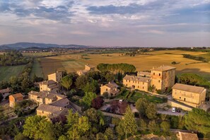 A rural village with stone buildings, surrounded by fields and trees.