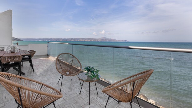 A terrace with wicker chairs, a table, and a view of the sea. - Mario Luxury Seafront Penthouse with Jacuzzi – Casa di Mario, Kalyves, Crete (Kalives)