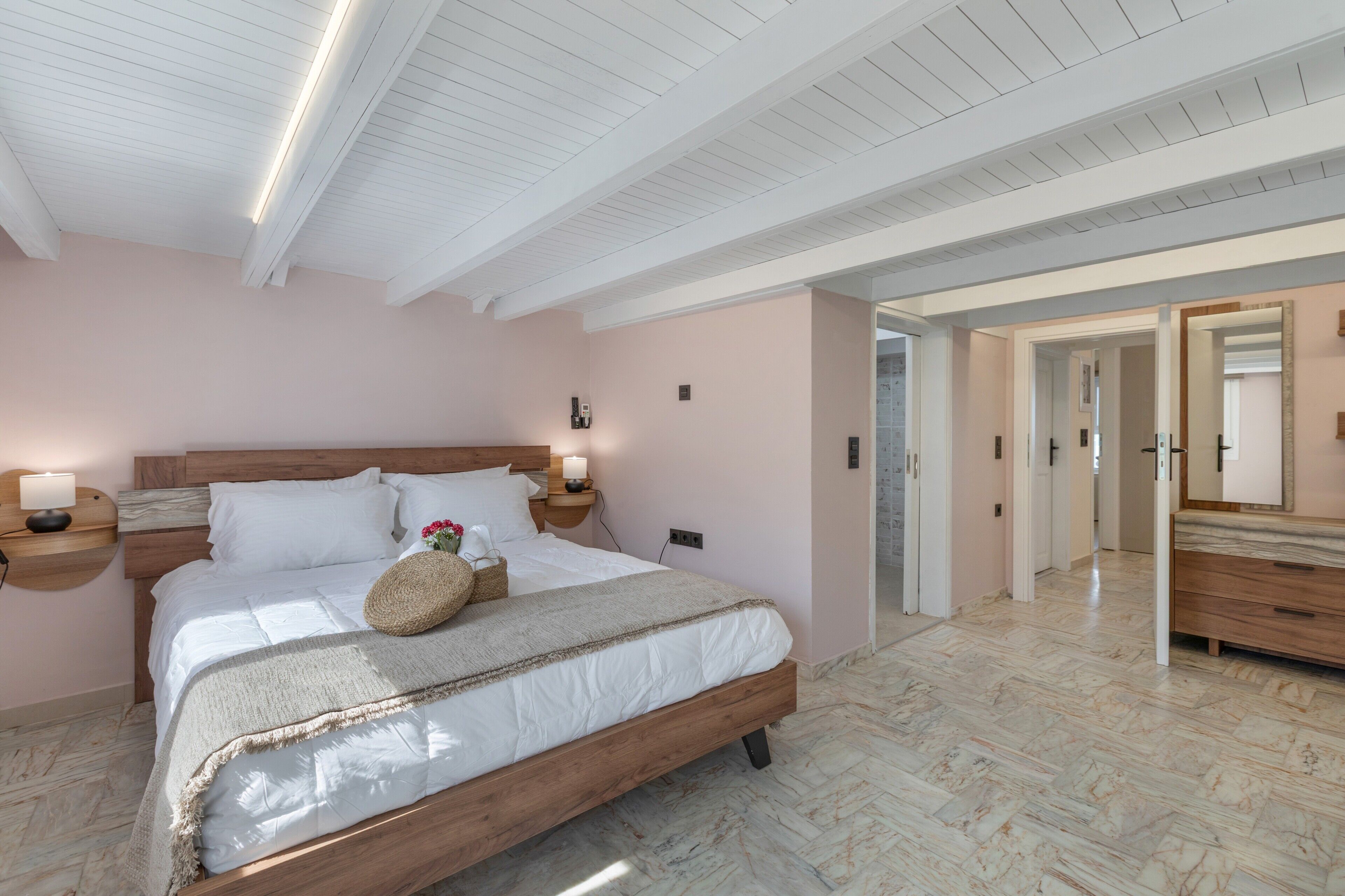 A bedroom with a wooden bed, bedside lamps, a nightstand, and a mirror.