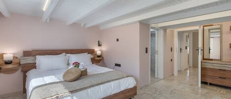 A bedroom with a wooden bed, bedside lamps, a nightstand, and a mirror.