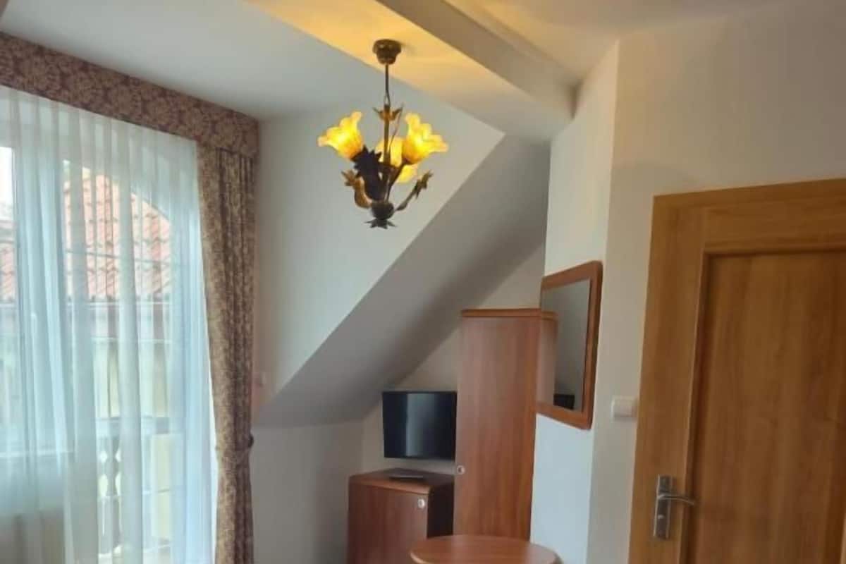 Habitación de hotel con dos camas, televisión, mueble de madera, una mesita redonda y una puerta.