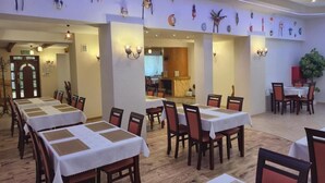 Un restaurante con varias mesas y sillas, suelo de madera y decoración mural.