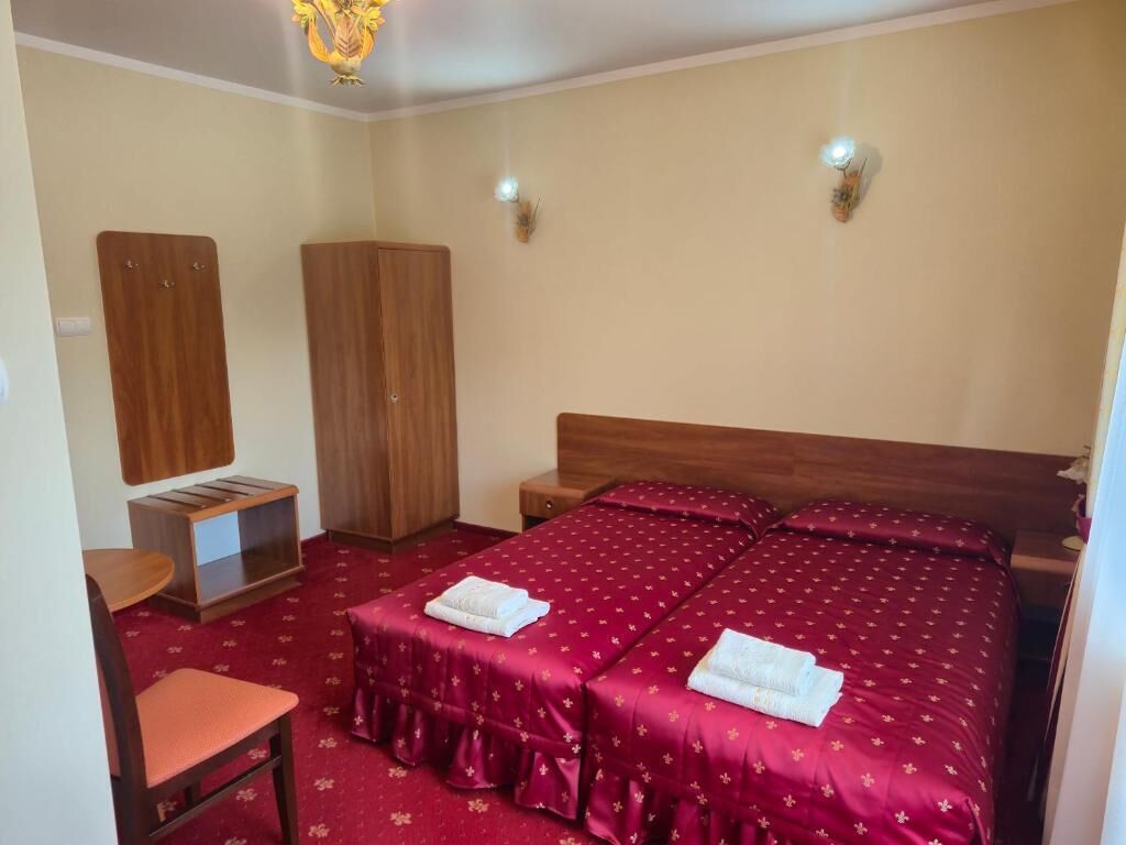 Habitació d'hotel amb un llit, dues taules de nit, un armari de fusta, una cadira i una taula petita.