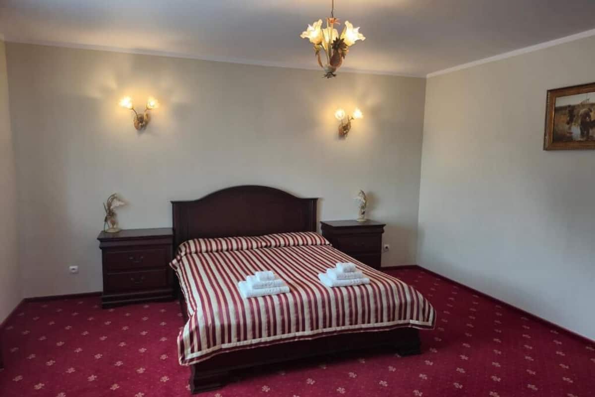 Un dormitorio con una cama grande, dos mesitas de noche, un candelabro y apliques de pared.