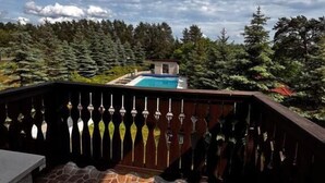 Un patio con piso de piedra, una piscina y vistas a zona boscosa.