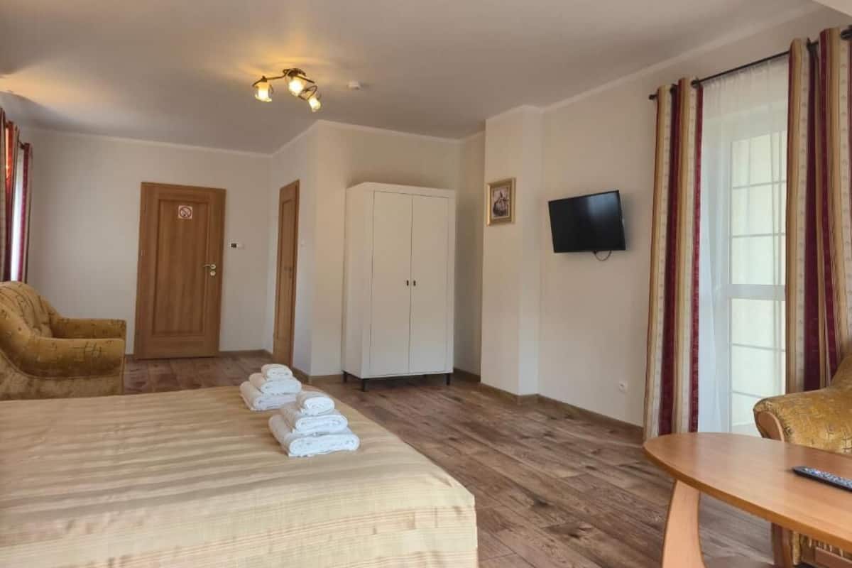 Una habitación de hotel con una cama, una silla de madera, un televisor y un armario.