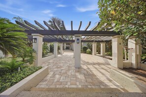 A covered walkway with a pergola structure, surrounded by landscaped gardens and palm trees. - Cozy Dr Phillips Condo Near Universal Studios (Orlando)