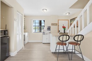 A modern kitchen with white cabinets, a microwave, and a coffee maker. There is a window with a view of greenery outside. - Cozy Dr Phillips Condo Near Universal Studios (Orlando)