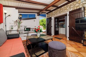 A cozy living area with a sofa, a table with a vase of flowers, and a television. - Family-friendly vacation home in Selce - 100 m to the beach & center (Crikvenica)