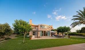 Ein modernes, zweistöckiges Haus mit Terrasse, Gartenmöbeln und einem gepflegten Rasen.