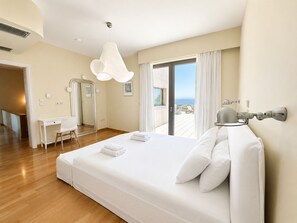 Een hotelkamer met een groot bed, een bureau, een stoel, een spiegel en een balkon met uitzicht.