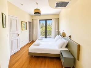 Une chambre d’hôtel avec un grand lit, une table de chevet, une fenêtre avec des rideaux et une vue sur la verdure.