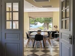 A dining area with a checkered floor, a table with chairs, and a view of the outdoors. - Superb Contemporary Luxury Holiday Villa Rental in - Afandou - sleeps 10 guests (Afantou)