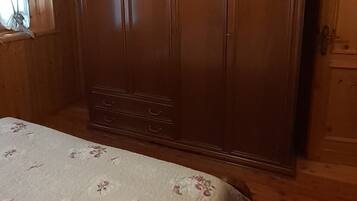 Una camera da letto con un armadio in legno, un letto con biancheria da letto a motivi floreali e un lampadario.