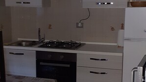 A compact kitchen with a gas stove, a sink, and a refrigerator.