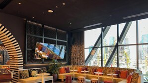 A modern lounge area with a sofa set, round tables, and a large TV screen. - LUX | The Five Star Modern Studio (Dubai)