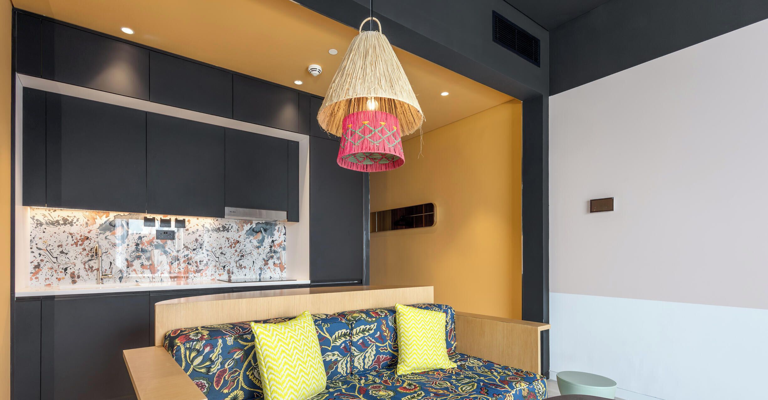 A modern room with a sofa, a hanging lamp, and a wall-mounted artwork.