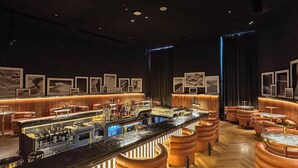 A bar area with a long counter, stools, and a bar stocked with bottles. - LUX | The Five Star Modern Studio (Dubai)