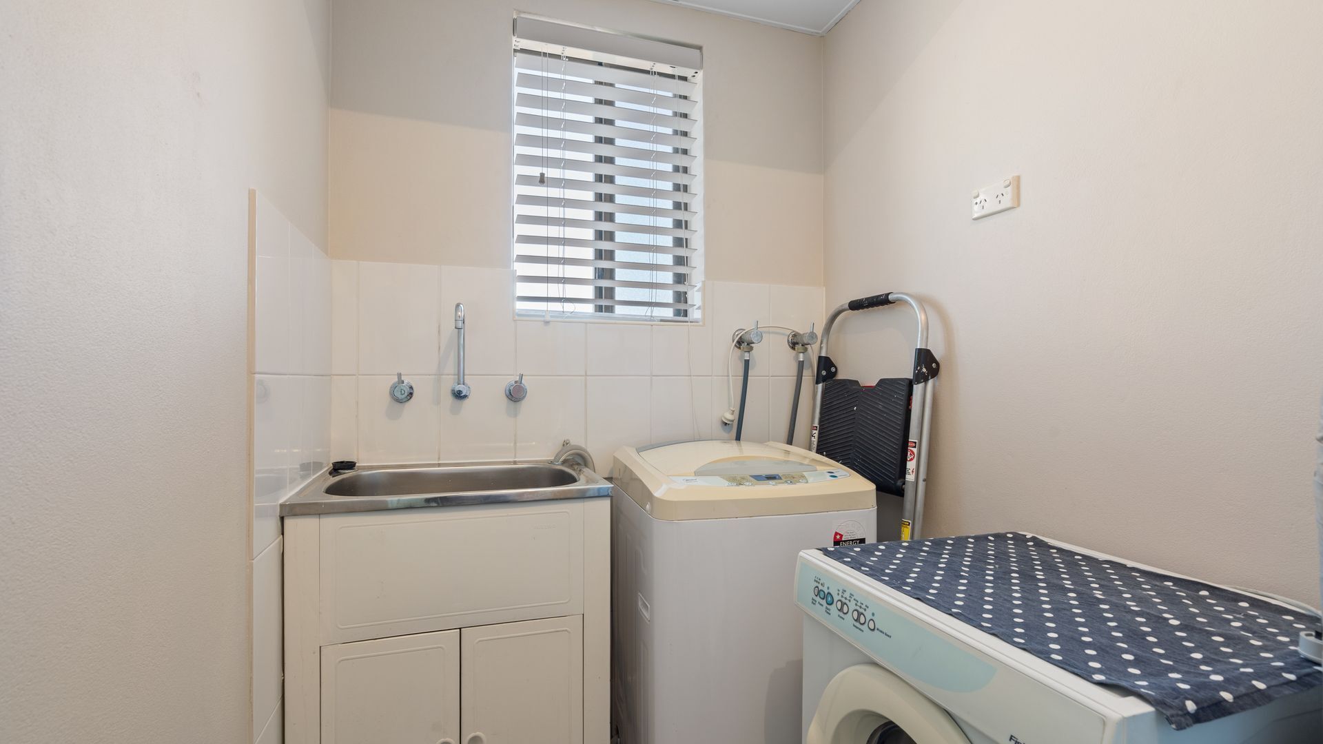 Ein kleines Badezimmer mit Waschbecken, Toilette, Dusche und Waschmaschine.