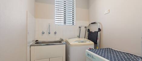 Ein kleines Badezimmer mit Waschbecken, Toilette, Dusche und Waschmaschine.
