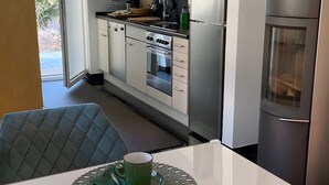 Una cocina moderna con armarios blancos, un refrigerador de acero inoxidable y un comedor con mesa y sillas.