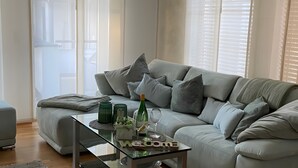 Una sala de estar moderna con un sofá gris, una mesa de centro de vidrio y un cartel que dice 'Welcome'.