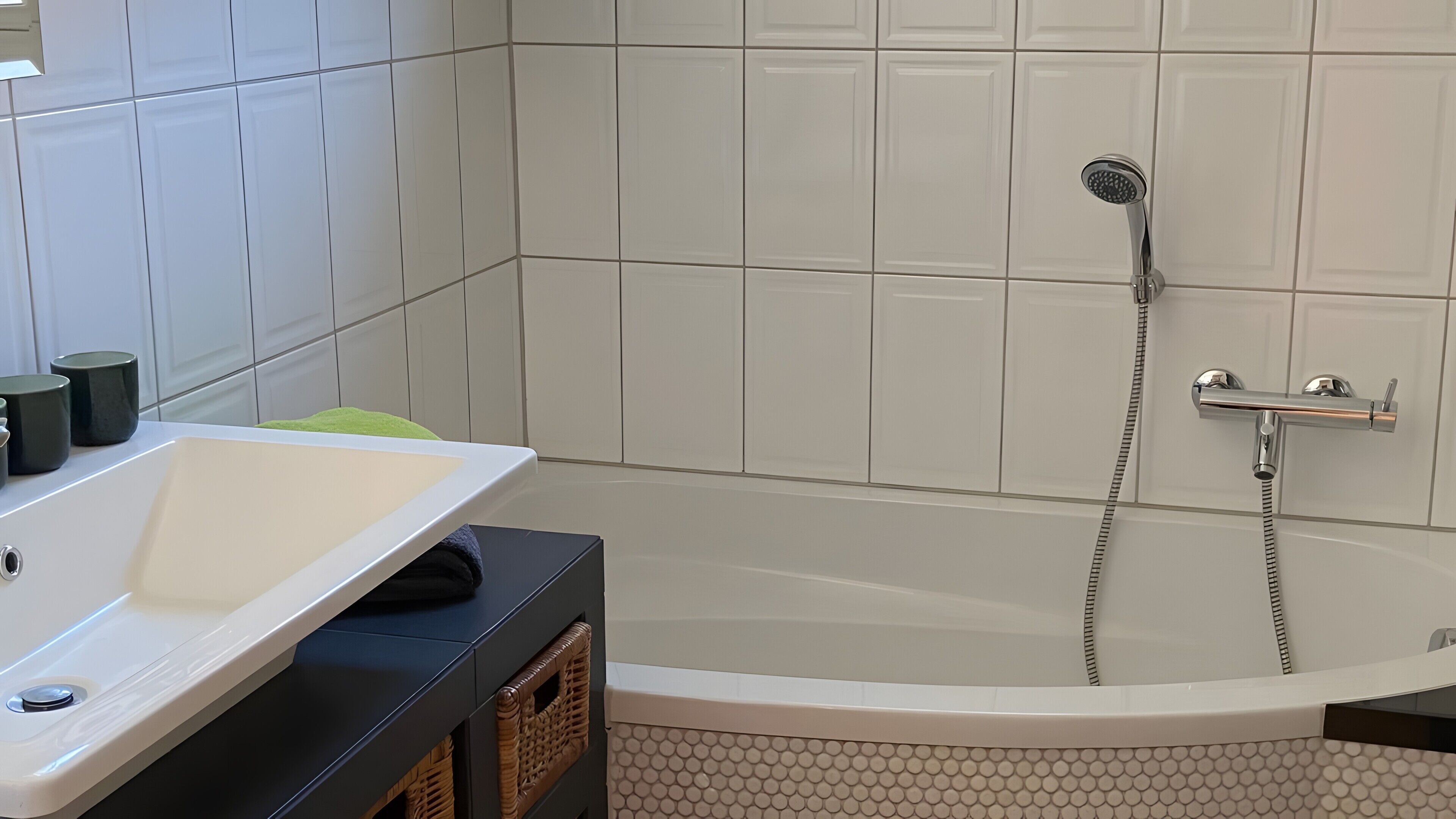 Uma casa de banho moderna com uma banheira independente, chuveiro manual e lavatório branco.