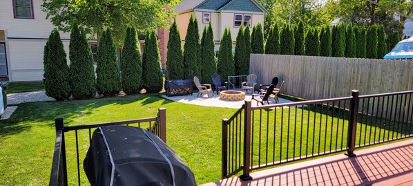 A backyard with a fire pit, outdoor seating, and a grill.