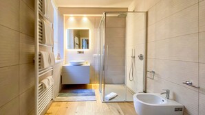 Een moderne badkamer met een douchecabine van glas, een wit wastafelmeubel en een toilet.