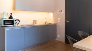 Een moderne keuken met een ingebouwde magnetron, koffiezetapparaat en waterkoker.