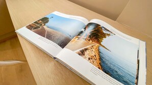 Un magazine ouvert dont les pages présentent des paysages côtiers et des structures architecturales.