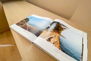 An open magazine with pages displaying coastal landscapes and architectural structures. - Time to Be - COTONE  Luxury Apartments (Peschiera del Garda)