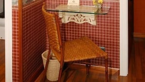 A bathroom with a glass sink, a chair, a wall-mounted light, and a framed picture above the mirror. - Hotel Avenida Real (Villaviciosa)