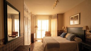 A hotel room with a large bed, a bench, a chair, a mirror, and a painting on the wall. - Hotel Avenida Real (Villaviciosa)