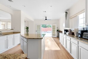 A spacious kitchen with white cabinetry, granite countertops, and a central island. - Large Groups' Luxury House Pool Sleep 22 (Round Rock)