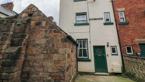 A building with a sign reading 'CROWN TERRACE,' stone walls, and a green door. - Crown Cottage (Belper)