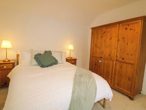 Ein Schlafzimmer mit einem Bett, zwei Nachttischlampen, einem Holzschrank und einem Nachttisch.