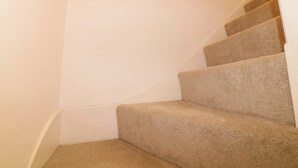 A carpeted staircase with a handrail, white walls, and a corner landing. - Crown Cottage (Belper)