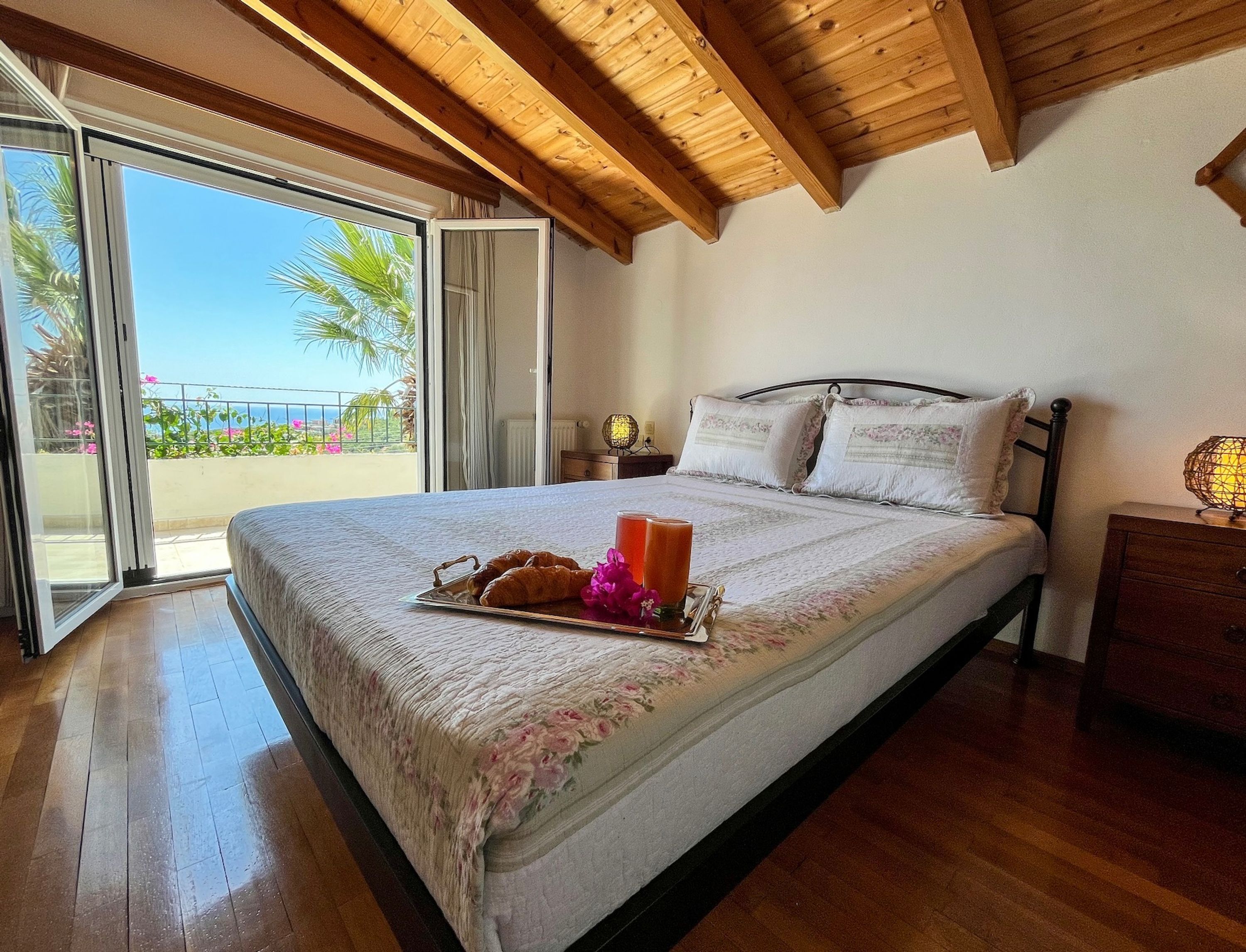 Un dormitorio con cama, mesita de noche, lámpara y vistas al exterior.