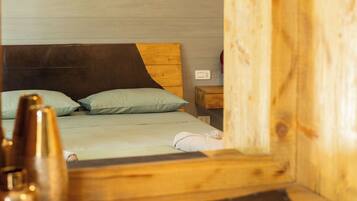A wooden cabin-style room with a bed, a nightstand, and a television mounted on the wall.