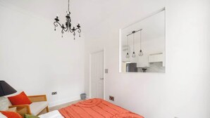 A bedroom with a bed, a chandelier, a mirror, and a door. - West Kensington 1-Bed | Private Garden | Sleeps 4 (Greater London)