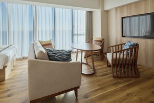 Una habitación de hotel con sofá, sillones, una mesita y televisión.