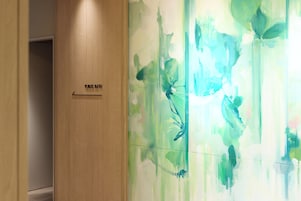 Una puerta de madera con un letrero que dice 'PUBLIC BATH' y una pared con arte abstracto en tonos verde y azul.