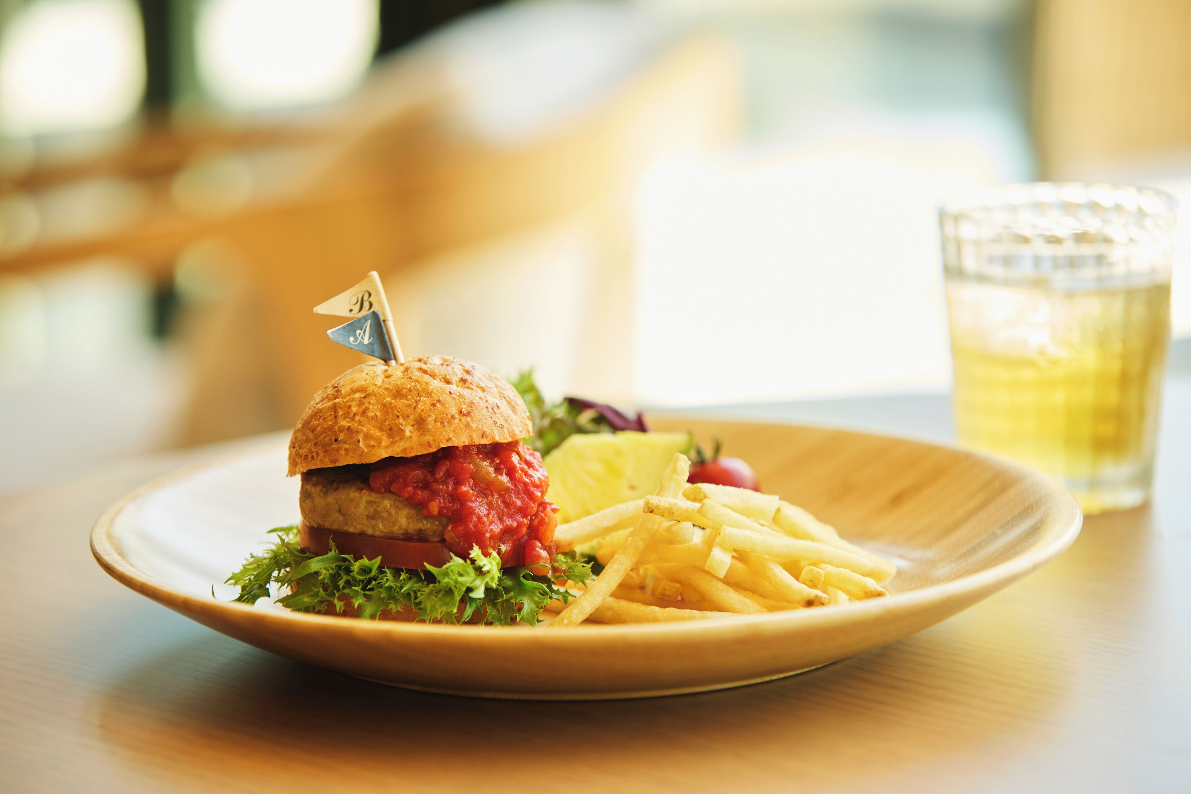 A plate with a burger, fries, and a drink on a table.